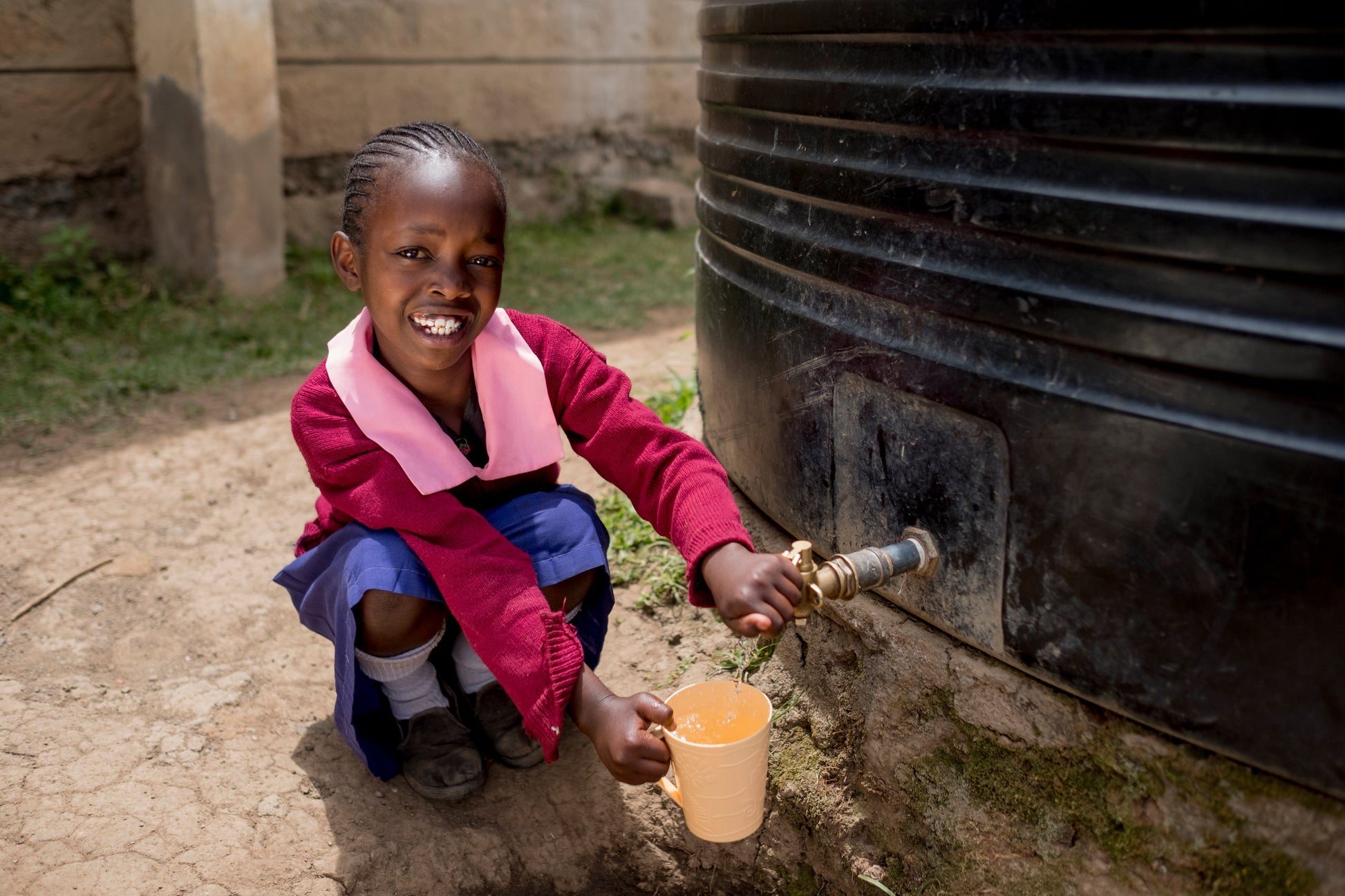 a girl sitting in front of a rainwater collection tank