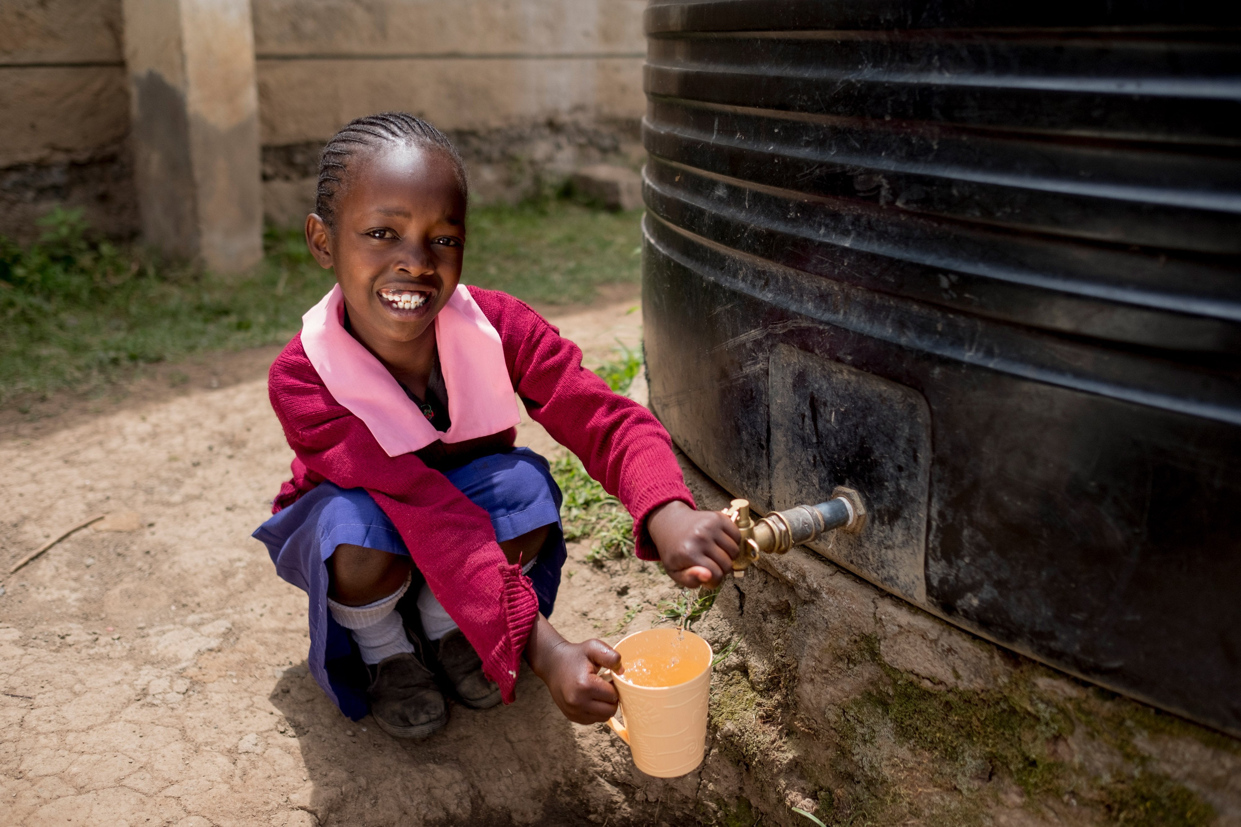 a girl sitting in front of a rainwater collection tank
