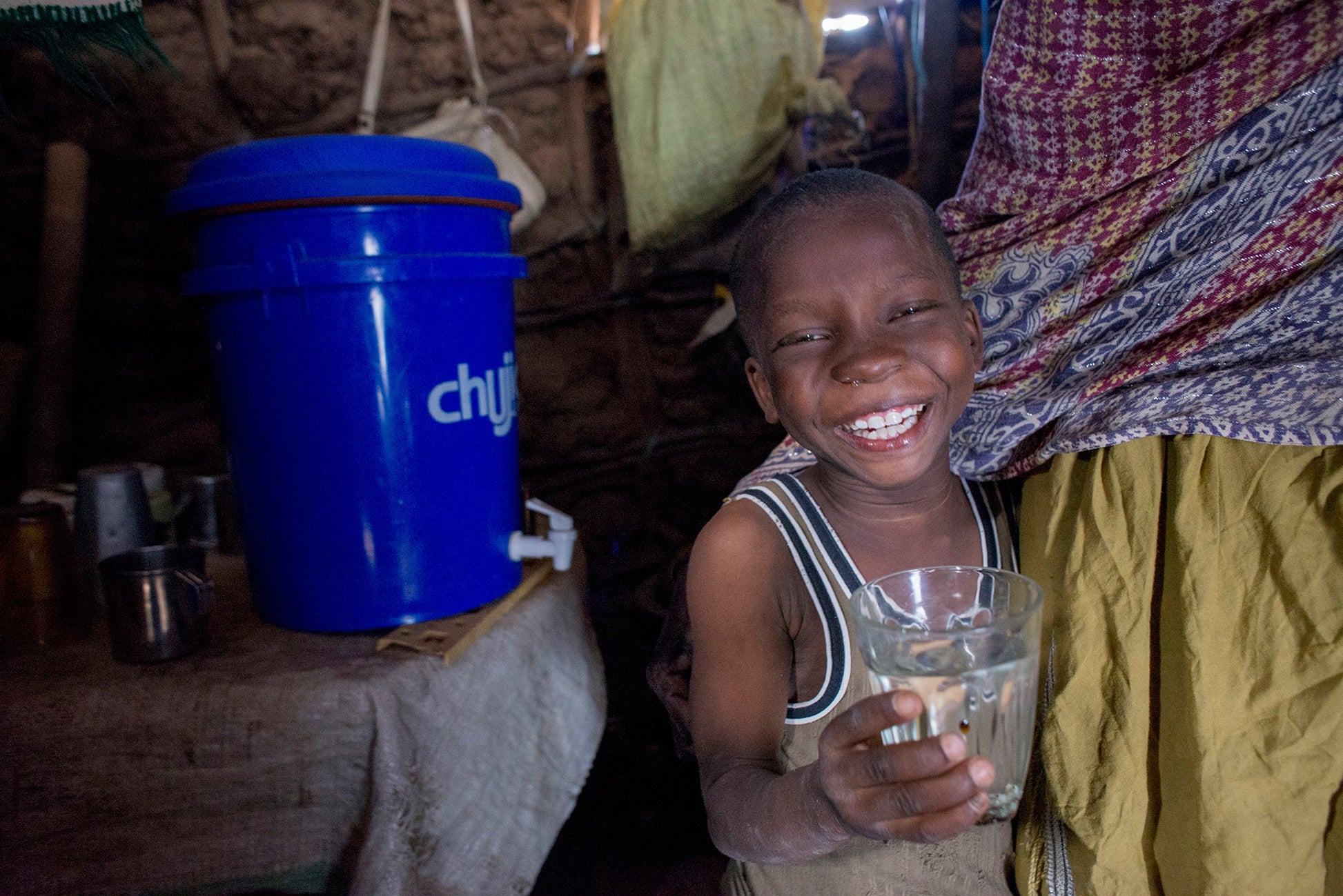 boy standing next to a water filter holding clean water