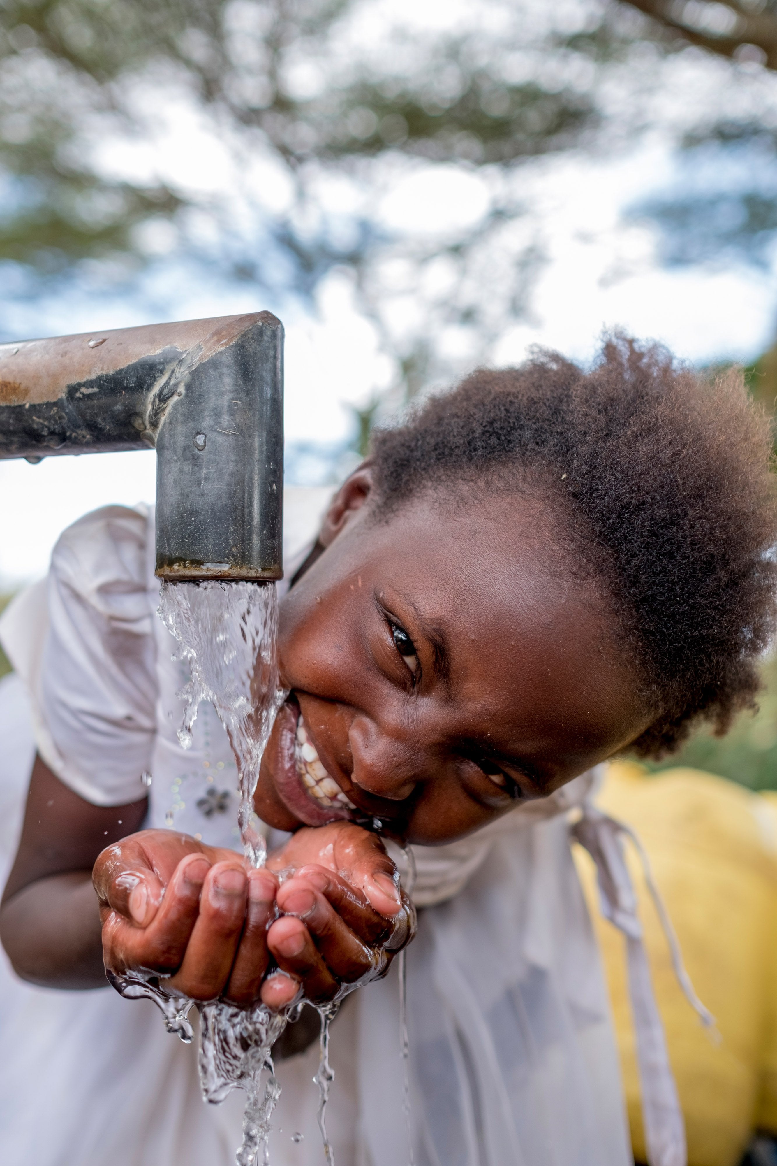 smiling girl bending over running well water