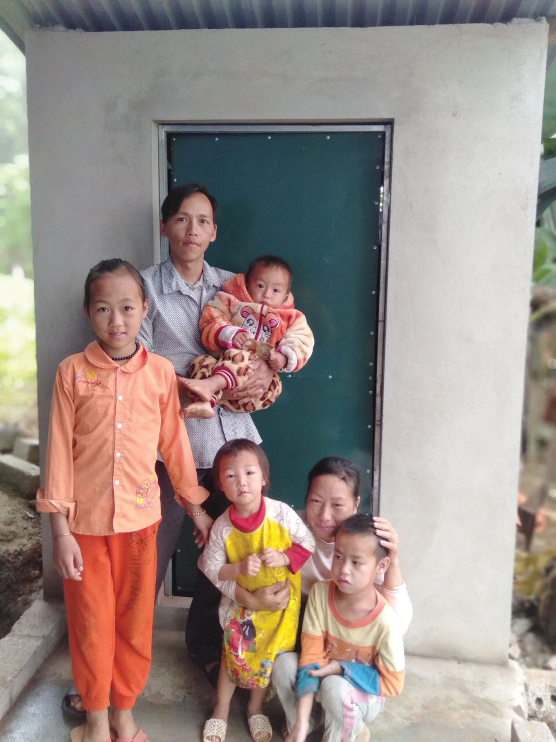A family stands in front of their new bathroom.